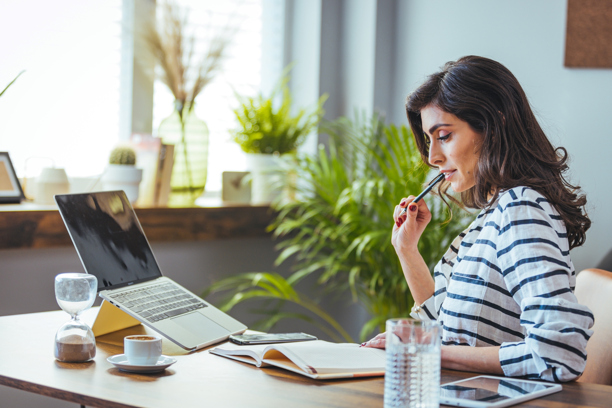 A shot of a young woman using a laptop and going through paperwork while working from home.